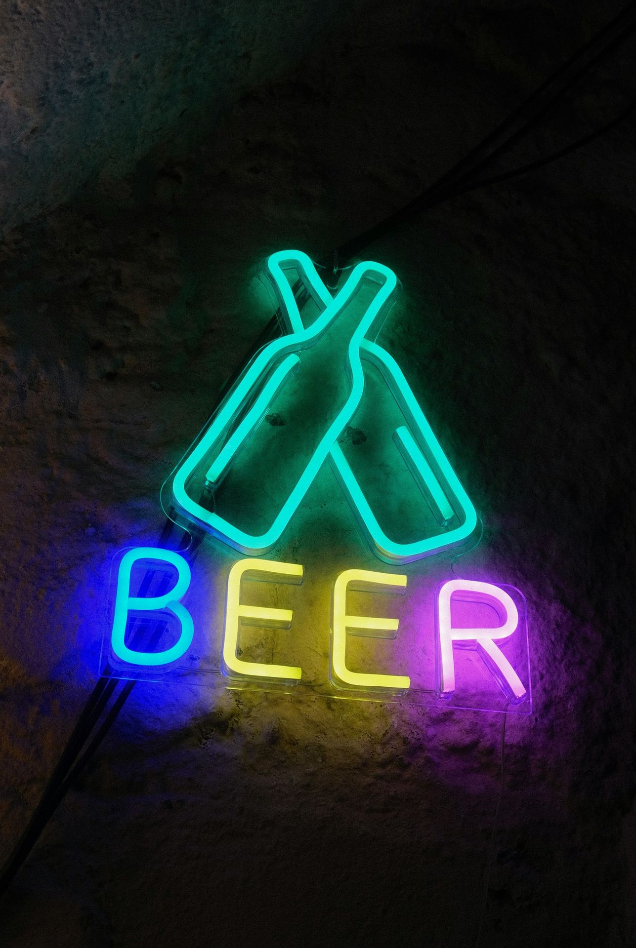Neon sign says "beer" with beer bottles.